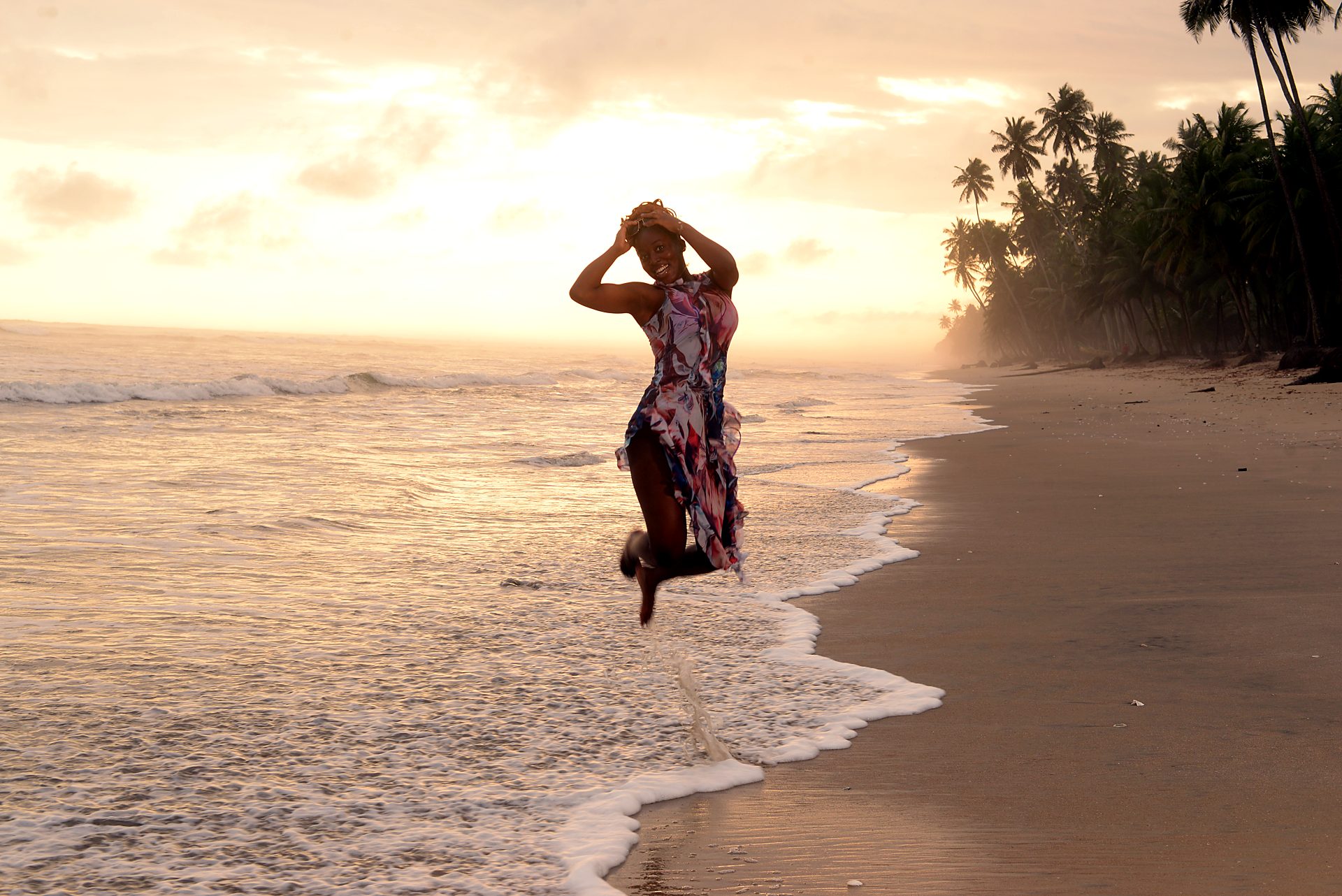 A guest leaping on the beach at sunset, Venice View Beach Resort